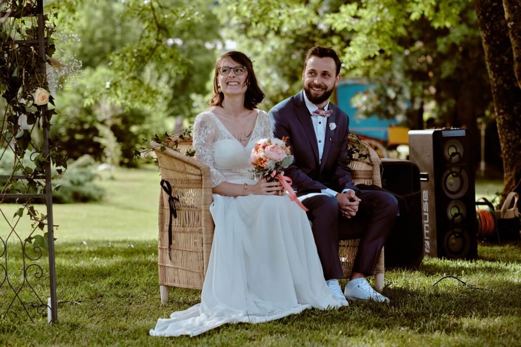 Les mariés assis dans des fauteuils en rotin pendant la cérémonie laïque