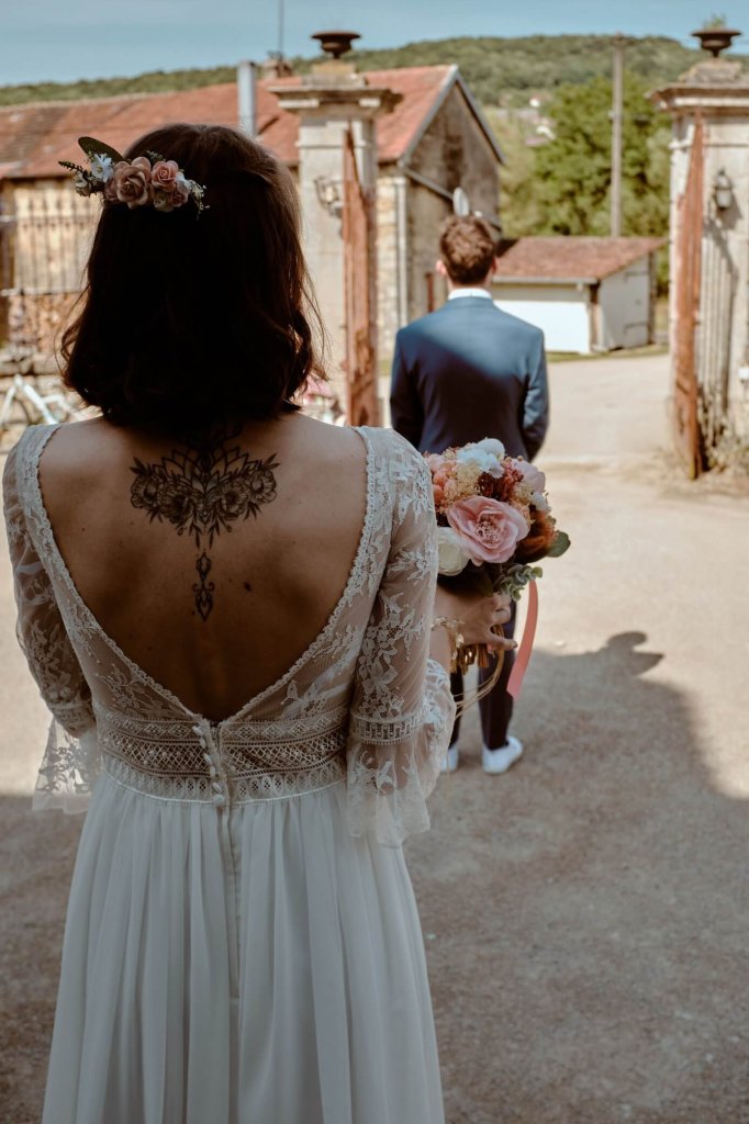 La mariée s'avance vers le marié, robe de dentelle au dos ouvert