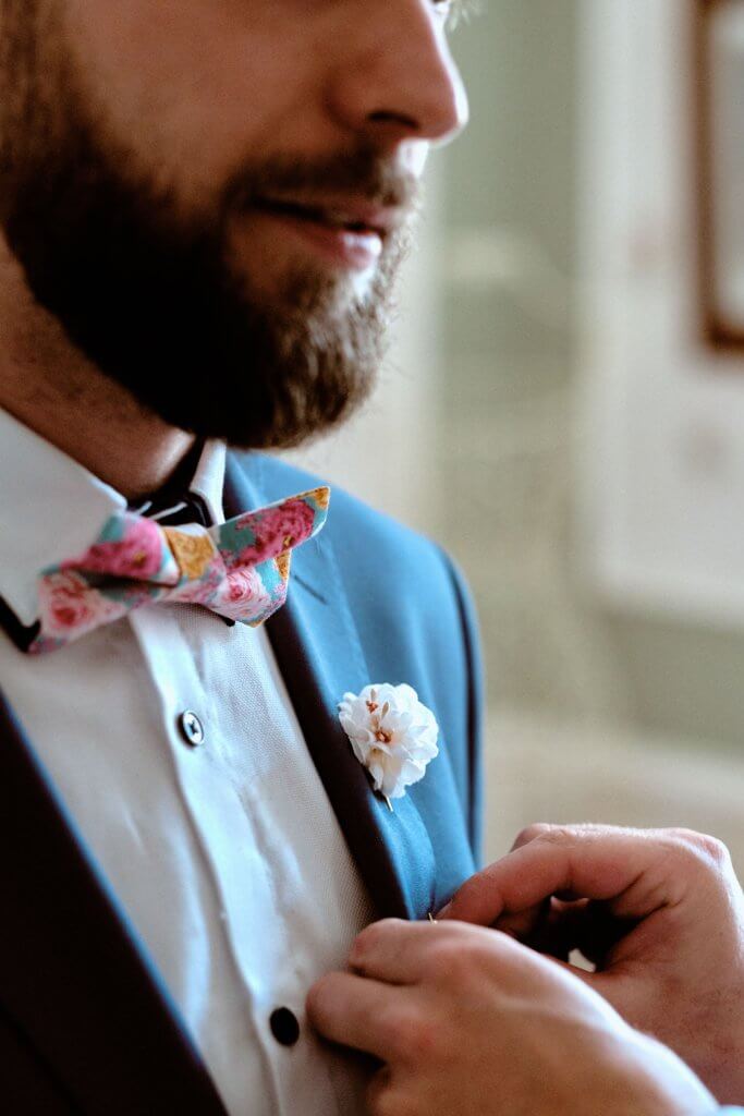 Le nœud papillon fleuri et la boutonnière du marié
