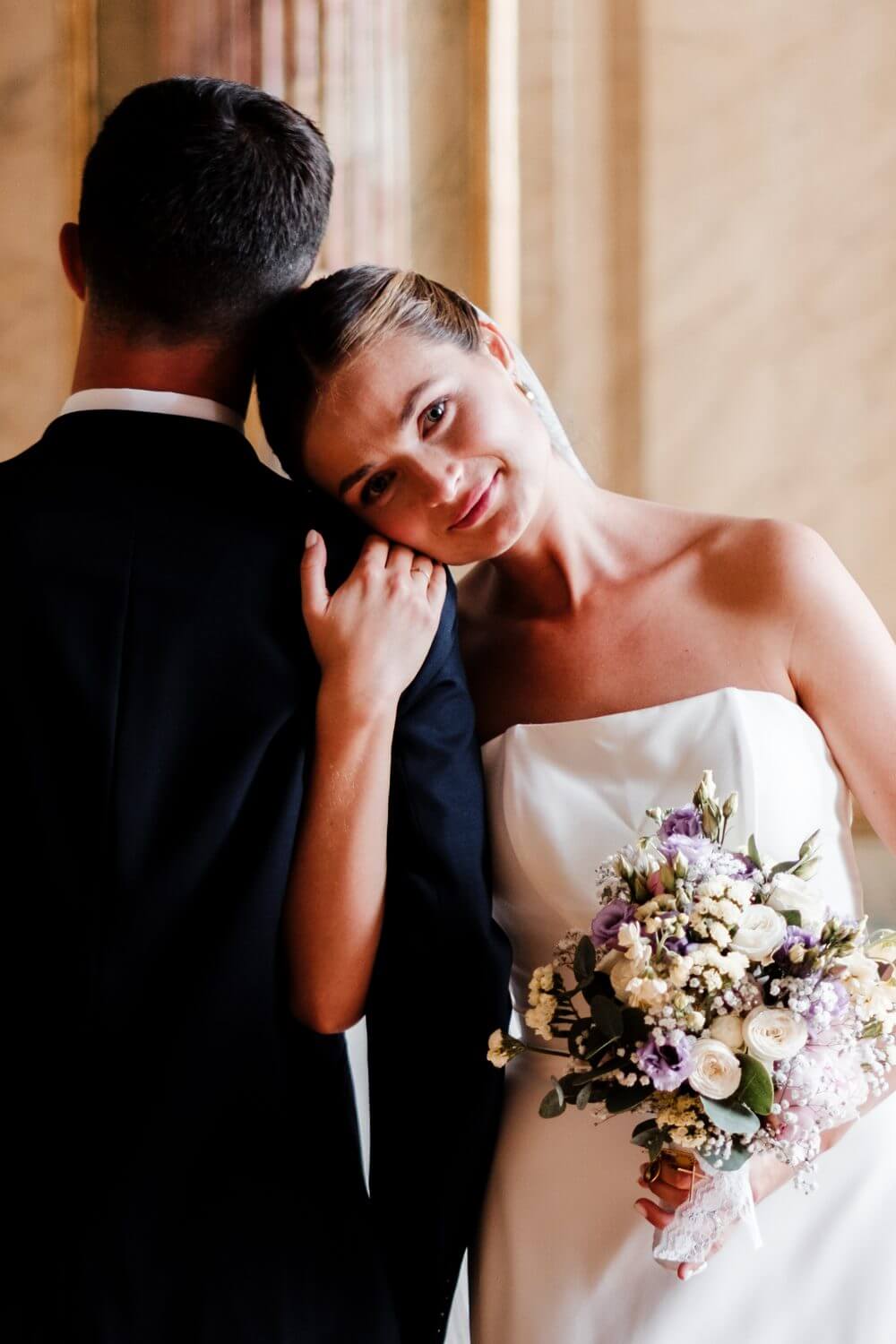 Mariage au Château des Rohan à Saverne : la mariée pose la tête sur l’épaule du marié dans la galerie dorée