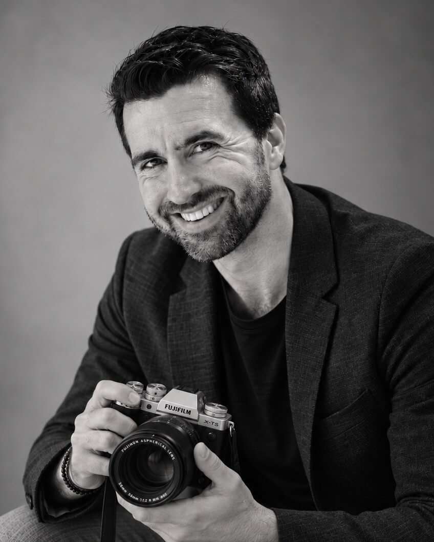 François Debeire, photographe de mariage en Alsace, assis, son appareil photo entre les mains