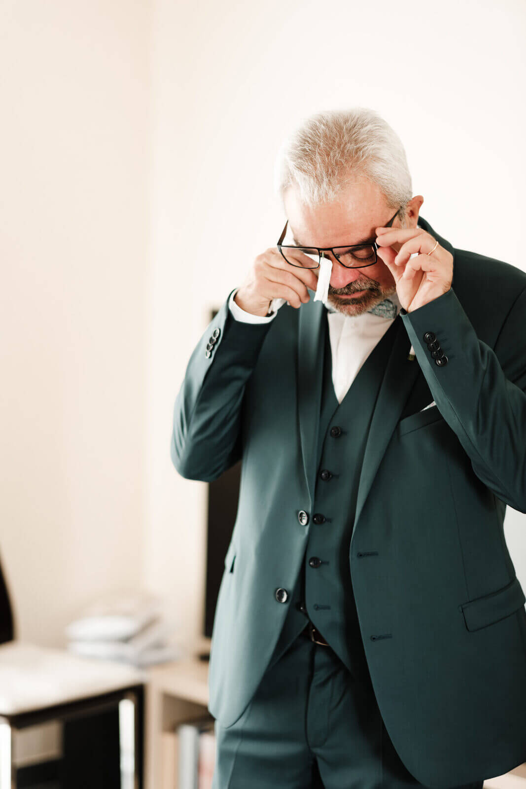 Un proche essuie ses larmes derrière ses lunettes en découvrant la mariée