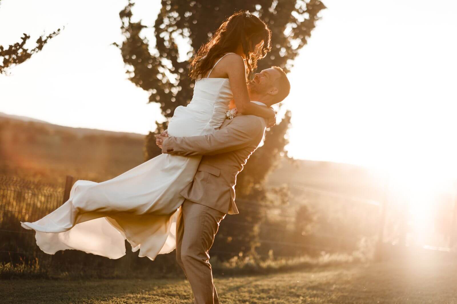 Le marié porte la mariée en contre-jour devant la plaine d’Alsace, en fin de journée